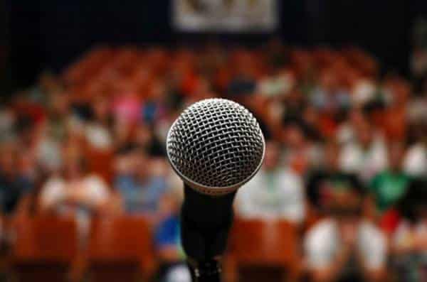 Microphone close up in front of a crowd in a speaking hall